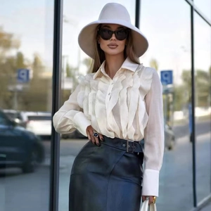 Elegant cream white ruffled long sleeve blouse with structured cuffs in a street style look