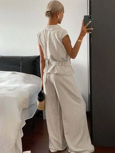 Detail of striped sleeveless top with waist belt and matching wide-leg trousers