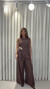 Detail view of brown striped v-neck sleeveless top and wide-leg trousers with waist belt