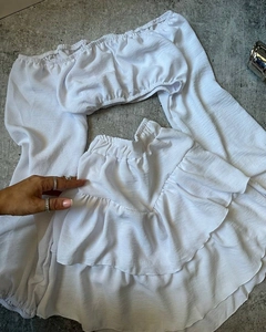 Detail von weißem schulterfreiem Crop-Top und Minirock mit Rüschen und Faltenstruktur
