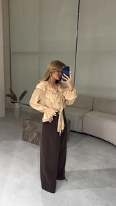 Détails de l'élégant chemisier en mousseline beige à volants avec cravate au col chic