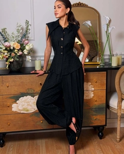 Close-up of black sleeveless top with golden buttons and textured jacquard fabric detail