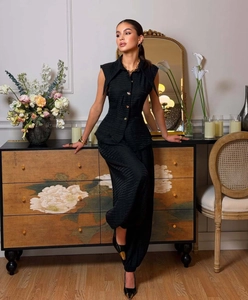 Detail of black peplum top with textured fabric and decorative buttons in a cozy setting