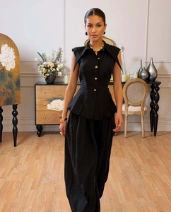Detailed view of the woven fabric texture and gold buttons on this elegant black peplum set