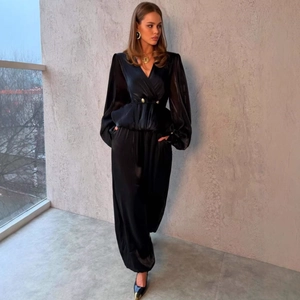 Elegante tuta in raso nero con scollo a V profondo, maniche a lanterna e volant in vita