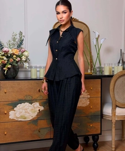 Detail of black sleeveless peplum top with gold buttons and textured jacquard fabric