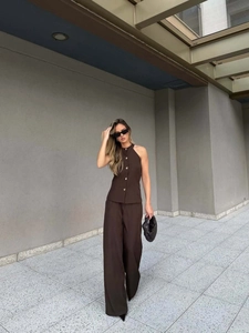 Detail of dark brown halter neck vest and high waist wide leg trousers on a model