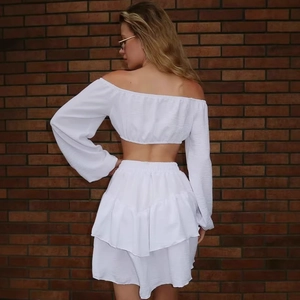 Eleganter weißer Zweiteiler mit schulterfreiem Langarm-Crop-Top und gestuftem Minirock