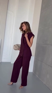 Detail of burgundy double-breasted vest and high-waist wide-leg trousers suit set