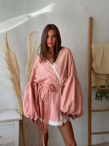 Detail of pink wrap dress featuring puffy lantern sleeves and delicate white lace trim