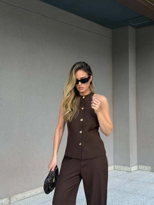 Detail of dark brown halter vest featuring four irregular gold buttons and matching trousers