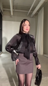 Dettaglio di elegante camicia in raso nero con scollo a fiocco e maniche a lanterna