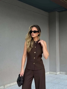 Detail of dark brown vest with unique gold buttons and matching wide-leg trousers