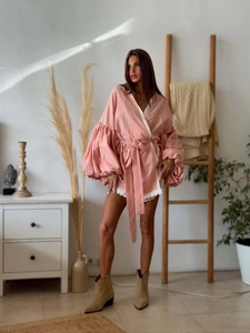 Pink lace-trimmed wrap top featuring voluminous lantern sleeves and tie-waist detail