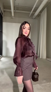 Dettaglio di camicia in raso a maniche lunghe con balze e minigonna a pois
