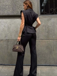 Detail of black peplum sleeveless vest and matching wide-leg trousers on a model