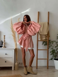 Pink balloon sleeve mini dress with lace trim and waist tie shown in a lifestyle scene