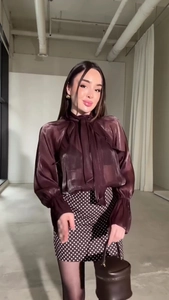 Vista intera di camicia marrone trasparente con fiocco e minigonna a pois con borsa secchiello