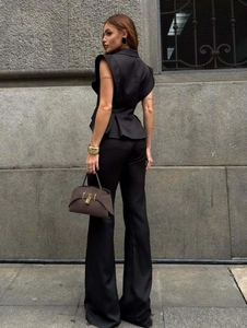 Detail of elegant black sleeveless peplum vest and high-waisted wide-leg trousers