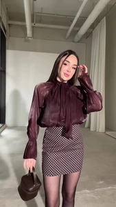 Dettaglio dell'elegante camicia in raso marrone scuro con grande fiocco e maniche lunghe