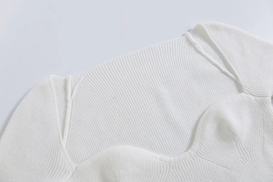 Dettaglio di maglione bianco a costine con scollo a cuore e finiture di alta qualità