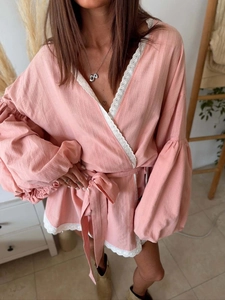 Detail of pink lace-up blouse with delicate lace trims and lantern sleeves on fabric