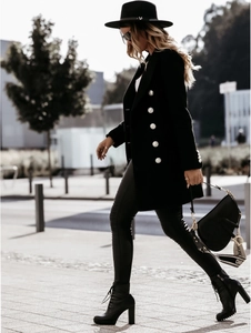 Outdoor shot of a black double-breasted wool coat with silver buttons and slim fit