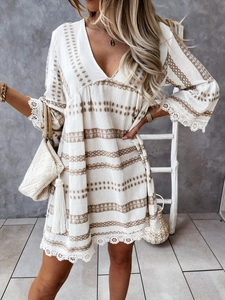Dettaglio dell'abito boho bianco con ricami geometrici marroni e bordo in pizzo fine