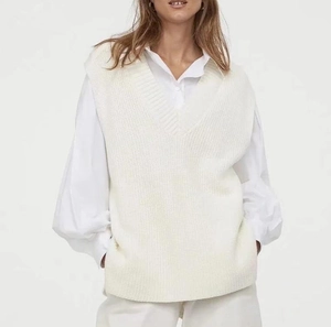 Detail of white V-neck knit sweater vest layered over a crisp white long sleeve shirt