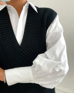 Detail of chunky ribbed knit V-neck vest layered over a white puff sleeve shirt