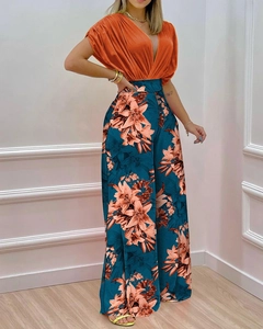 Détail du haut orange col en V avec un pantalon large à imprimé floral taille haute