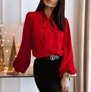 Detail of red lantern sleeve shirt featuring elegant bow-tie neck and draped fabric