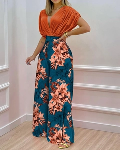 Détail du haut orange à col en V et du pantalon large à fleurs sur mannequin