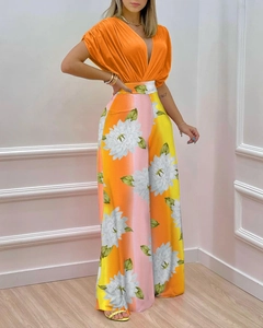 Détail du haut orange col V et du pantalon large avec imprimé floral en dégradé