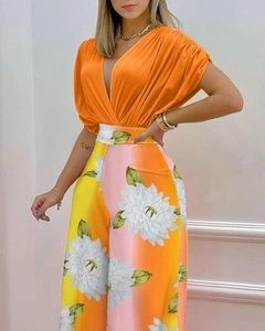 Gros plan sur le haut plissé à col en V orange et le pantalon ample à motif floral