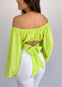 Détail d'un crop top vert néon à épaules dénudées avec un grand nœud au dos et manches bouffantes