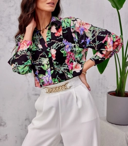 Detail of floral long sleeve shirt with gold chain belt on white wide-leg trousers