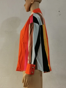 Détail de chemise patchwork montrant des poignets orange vif avec deux boutons argentés