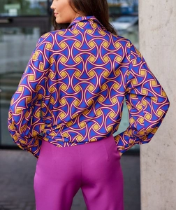 Détail de la chemise à imprimé géométrique et du pantalon magenta porté par un mannequin