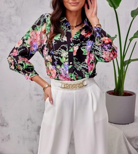 Detail of floral print shirt with golden buttons and white trousers with metal chain link