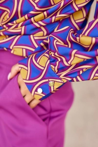 Détail de la manchette de chemise à fleurs avec boutons dorés et poche de pantalon fuchsia