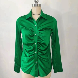 Dettaglio dell'elegante camicia in raso verde smeraldo con arricciature frontali e bottoni