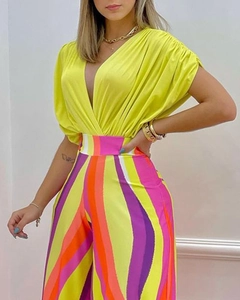 Détail du haut jaune néon à col en V profond et pantalon large à rayures colorées