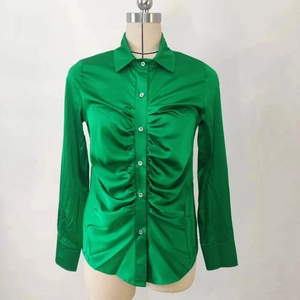 Dettaglio della camicia in raso da donna con eleganti pieghe arricciate e tessuto verde lucido