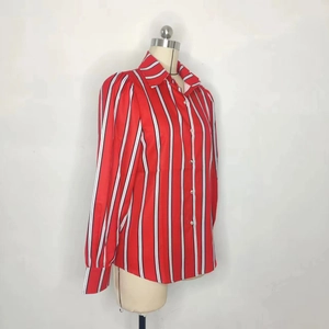 Détail de la chemise rayée rouge et noire avec poignets boutonnés et texture de tissu