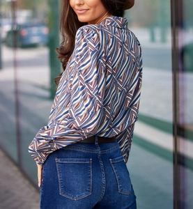Street style shot of a geometric print long-sleeve blouse paired with dark denim jeans