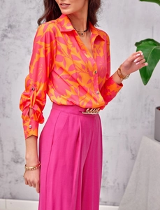 Detail of floral print long sleeve shirt with vibrant pink wide leg trousers and gold belt
