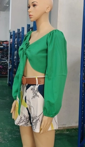 Détail du haut vert col en V à nouer et d'un short imprimé avec ceinture marron