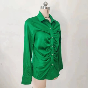 Dettaglio elegante camicia in raso verde brillante con pieghe arricciate e trama liscia