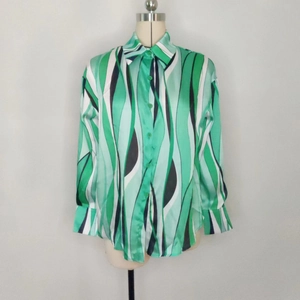 Dettaglio della camicia in raso verde con stampe a onde e polsini classici a bottone
